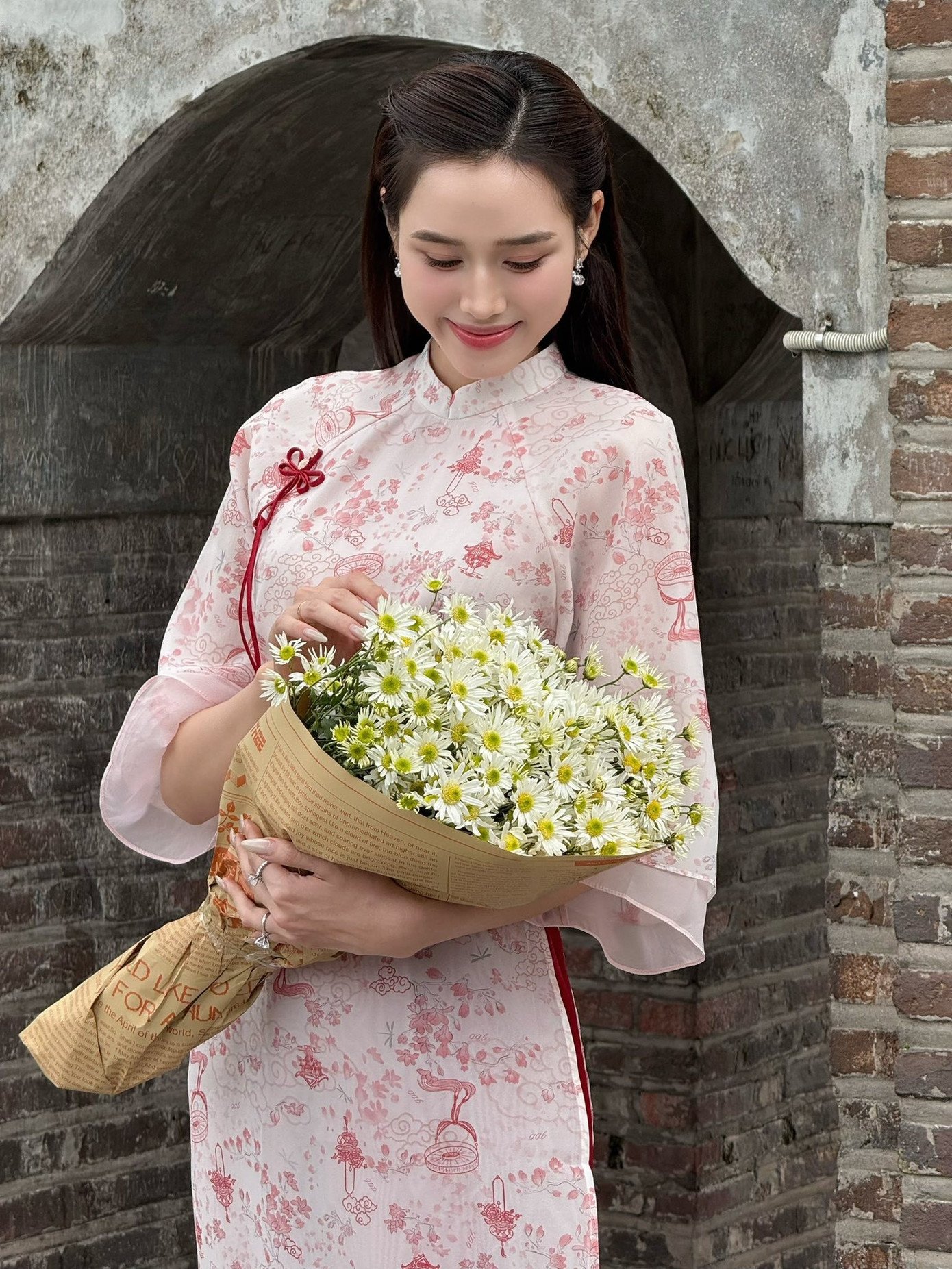 Từ năm ngoái, áo dài 4 tà đã được yêu thích và đến bây giờ, xu hướng này vẫn chưa hạ nhiệt. Hoa hậu Đỗ Thị Hà cũng khéo léo chọn thiết kế 4 tà màu hồng nhạt nhẹ nhàng, nữ tính nhưng không hề đơn điệu nhờ chiếc quần màu hồng đậm làm điểm nhấn.