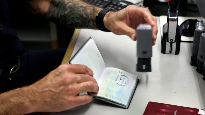 Nhân viên xuất nhập cảnh đang đóng dấu vào hộ chiếu cho du khách. Ảnh: NYT
