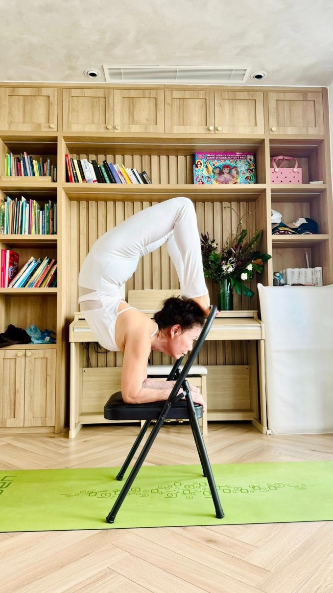 Bà Ngọc Hương thực hiện động tác Vrischikasana trên ghế.