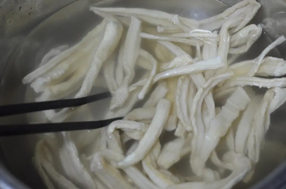 Cho củ cải khô vào thau lớn. Đổ nước sôi vào, dùng đũa đảo để củ cải mềm ra (không cần ngâm lâu).