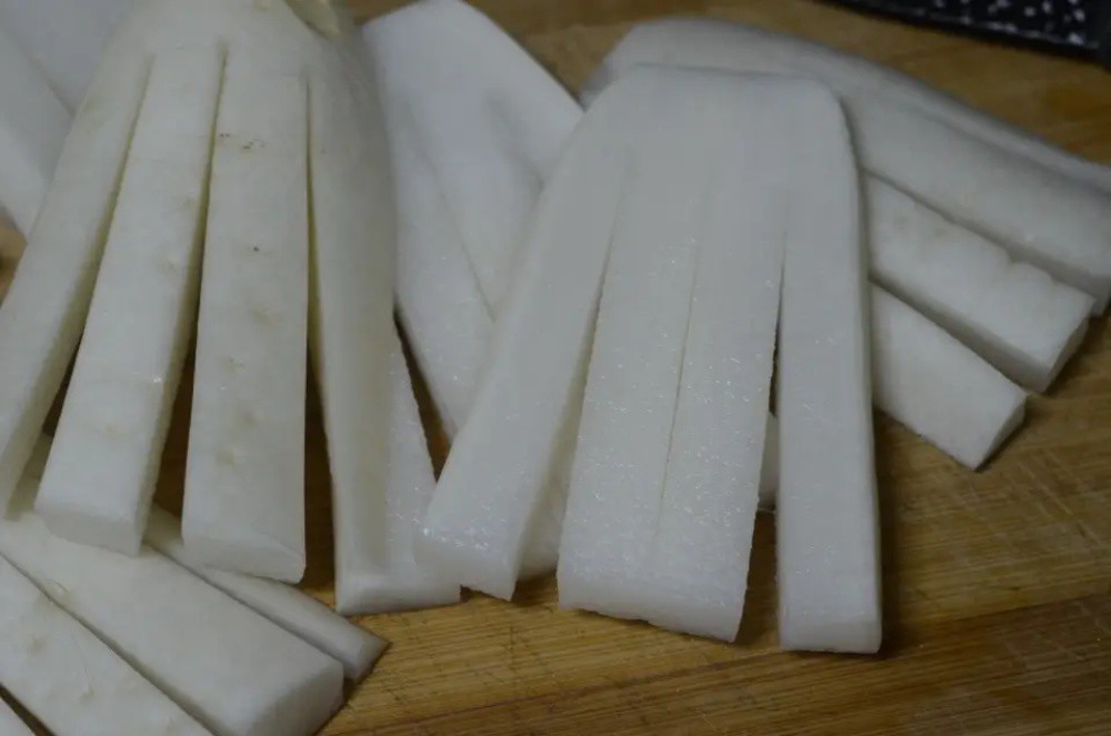  Một khúc củ cải thường cắt được 3–4 miếng, xẻ dọc mỗi miếng thành 3 sợi, đầu vẫn dính nhau để dễ phơi.