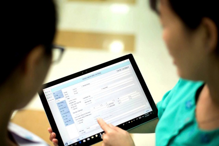 Y bác sĩ xem và nhập thông tin bệnh án của người bệnh ngay tại giường bệnh trên iPad. Ảnh: N.Phương