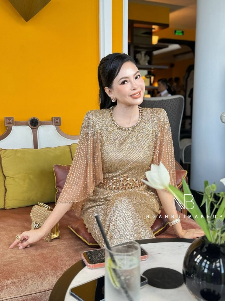 Thiết kế có giá khoảng 5.000 USD (130 triệu đồng), với phần vai độn vuông vức, ống tay loe, nhấn bằng chi tiết đính cườm và đá ở eo. Người đẹp phối trang phục với túi xách cùng tông của Dolce &amp; Gabbana - thương hiệu cô yêu thích và theo đuổi nhiều năm nay. Doanh nhân được chuyên gia Ngân Bùi trang điểm tông cam đất để ăn ý với bộ váy. Ảnh: Ngân Bùi