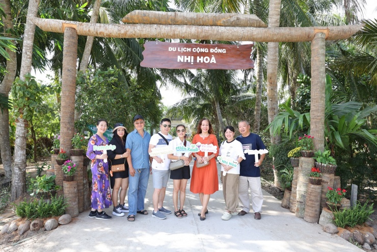 Du khách check-in bên cổng chào Làng du lịch cộng đồng Nhị Hòa.