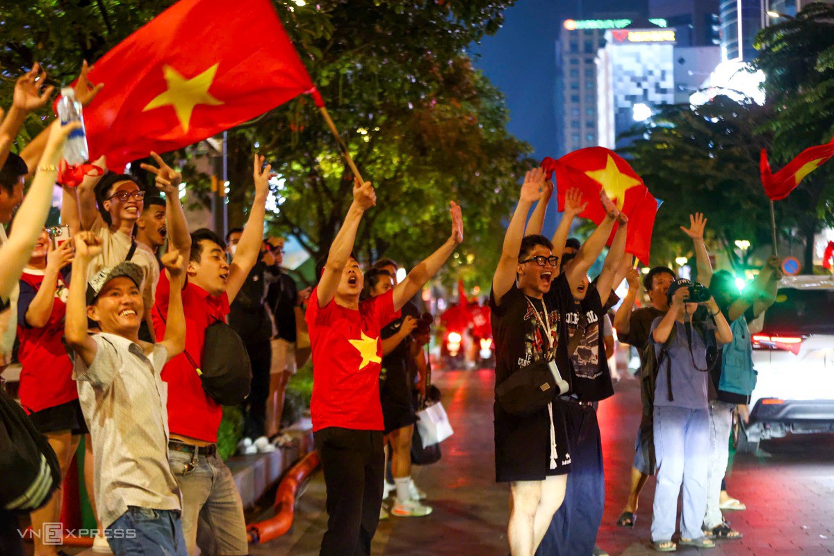 Nhóm cổ động viên hò reo, vẫy cờ mừng chiến thắng trên phố đi bộ Nguyễn Huệ. Ảnh: Quỳnh Trần