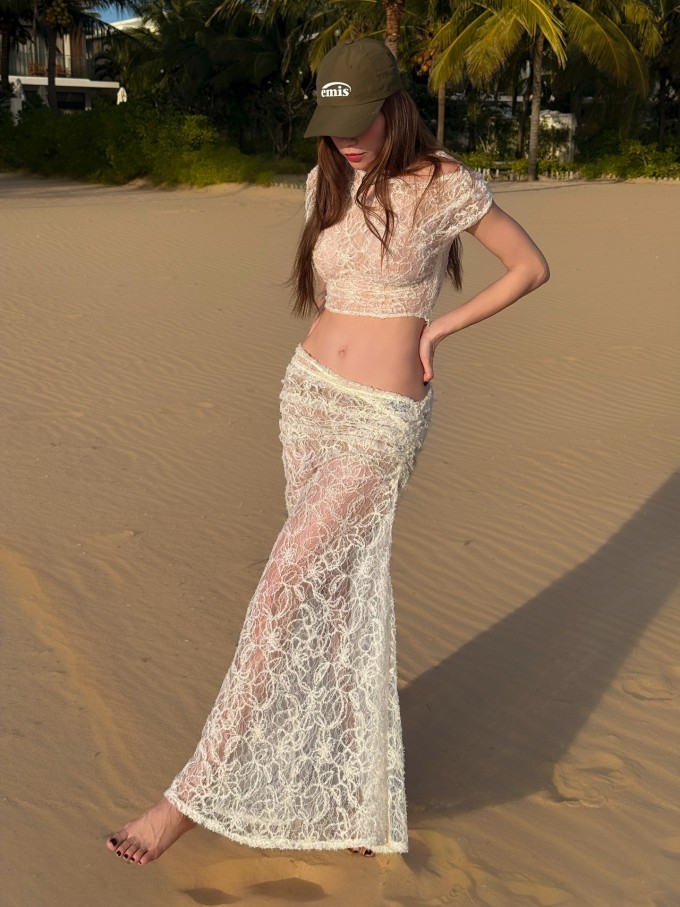 Ca sĩ tranh thủ tận hưởng khoảnh khắc thư thái khi nghỉ dưỡng tại một resort, đắm chìm trong ánh nắng nhẹ nhàng của bình minh ven biển. Bộ váy dạo biển chất liệu xuyên thấu của một local brand giúp bà mẹ ba con khoe tối đa vẻ gợi cảm.