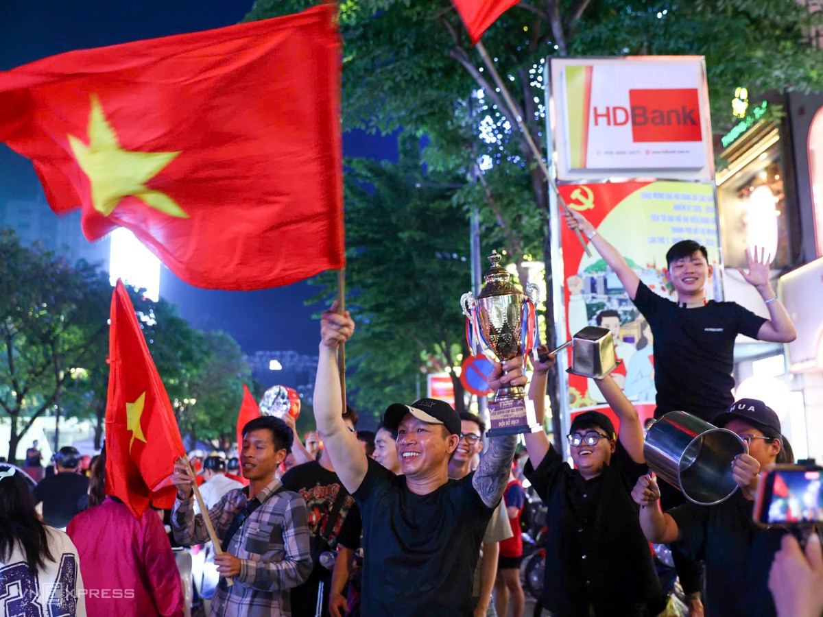 Người hâm mộ mang theo cúp tự chế, vừa vẫy cờ mừng đội tuyển. Ảnh: Quỳnh Trần