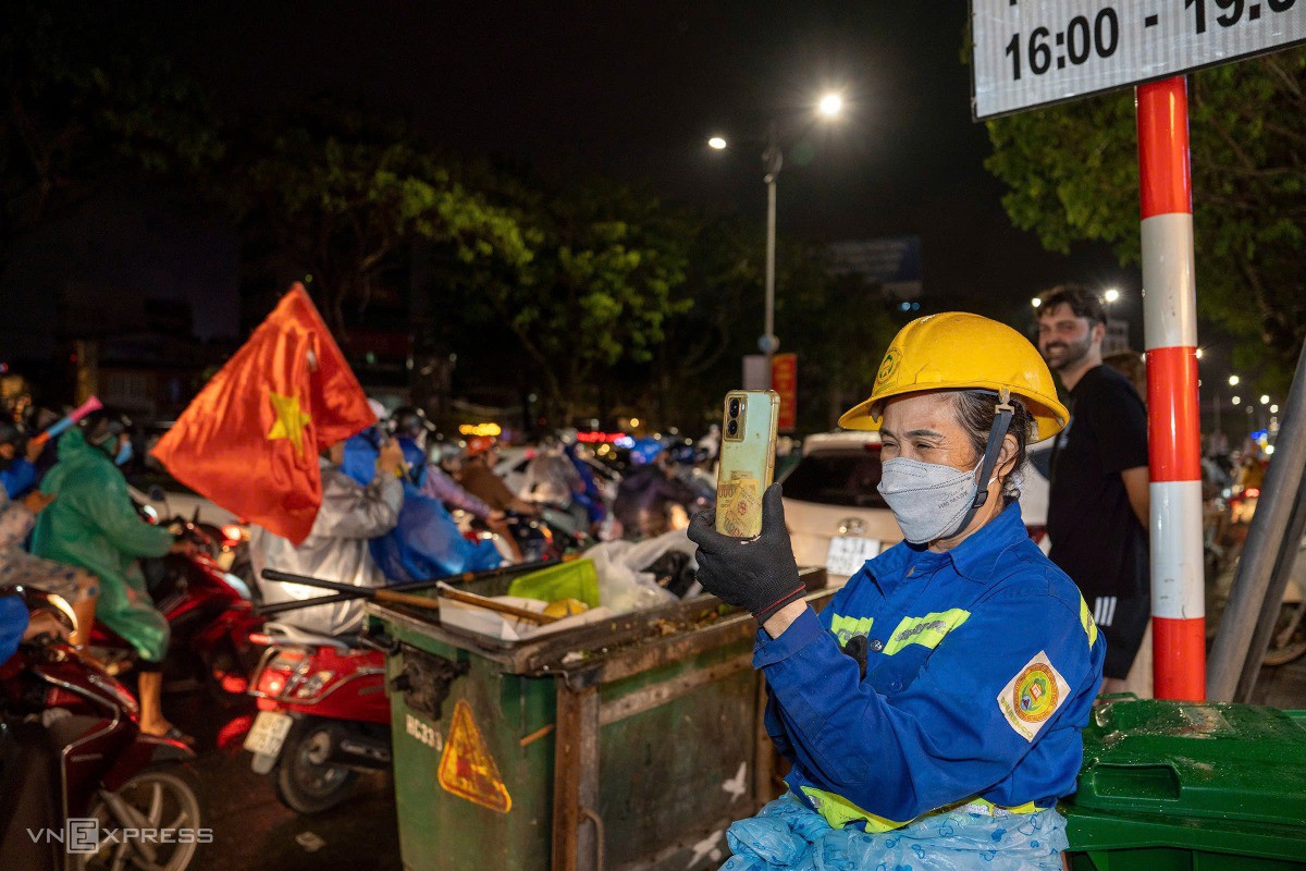 Nữ công nhân môi trường thích thú ghi lại cảnh người dân đi bão, khi tuyến phố đã chật kín xe không thể dọn dẹp. Ảnh: Nguyễn Đông