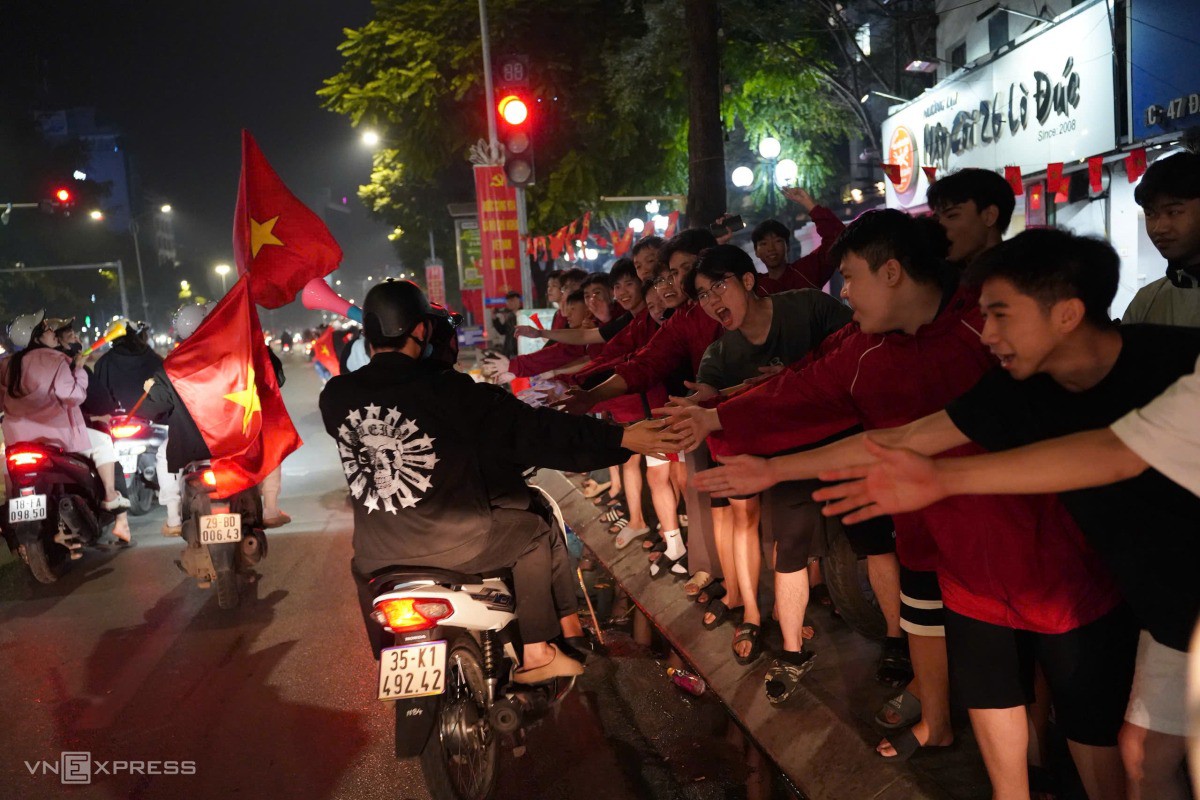 Trên đường Đại Cồ Việt, hàng dài các bạn trẻ đứng trên vỉa hè chìa tay chạm cùng người đi đường để ăn mừng. Ảnh: Hoàng Giang