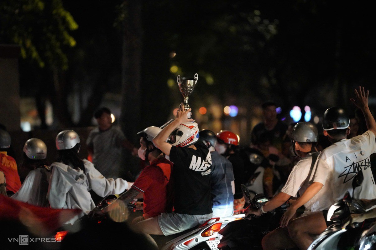 Người dân đi "đi bão" với mô hình cúp vô địch. Ảnh: Đăng Khoa