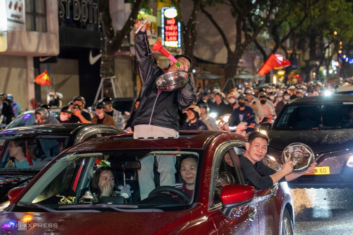 Hai người đàn ông mang theo các dụng cụ từ nhà bếp, nhờ phụ nữ lái xe để đi bão sau khi đã nâng ly mừng chiến thắng của Việt Nam trước Thái Lan. Ảnh: Nguyễn Đông