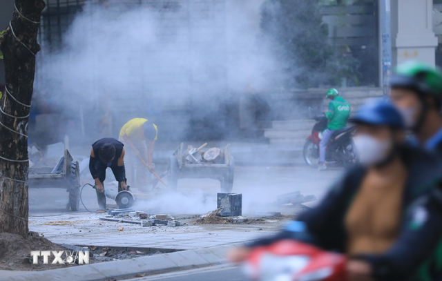 Công nhân cắt đá gây ô nhiễm môi trường khi thi công vỉa hè ở một khu phố Hà Nội. (Ảnh: Hoàng Hiếu/TTXVN)