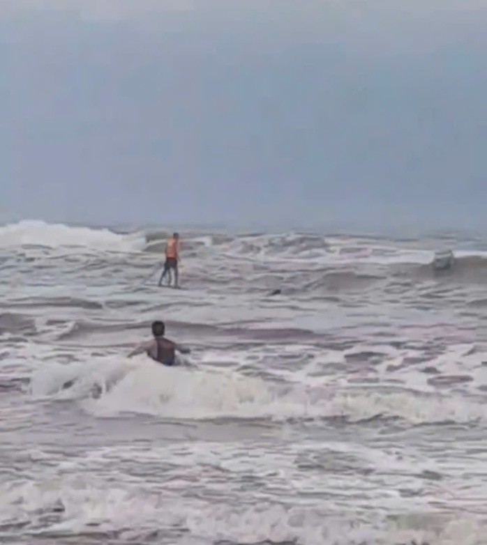 Bất chấp mưa lạnh, người dân Thế Mỹ A đã vượt qua sóng lớn để tiếp cận, cứu 2 ngư dân bị lật thuyền. Ảnh cắt từ clip.