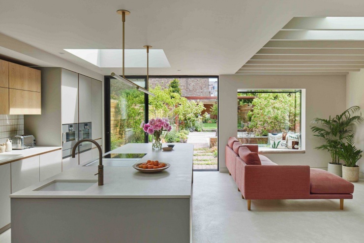Góc nhìn từ đảo bếp hướng ra phòng khách và khu vườn phía sau thông qua hệ cửa kính lớn. Thiết kế không gian mở giúp ánh sáng và mảng xanh lan tỏa sâu vào bên trong ngôi nhà. Nguồn: Archello