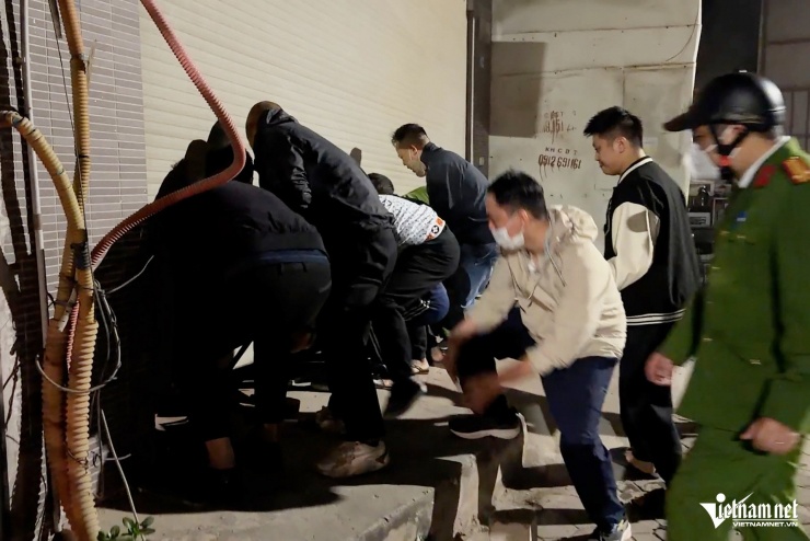 Hàng chục thanh niên giúp nhấc cửa, giải cứu 4 người mắc kẹt bên trong. Ảnh: Đình Hiếu