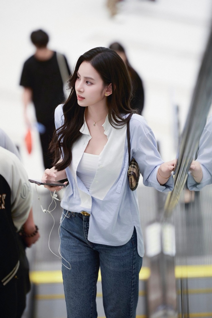 Người đẹp kết hợp sơ mi mở bung cúc cùng áo hai dây, quần jeans ôm dáng. Loạt phụ kiện đi kèm đều là hàng hiệu cao cấp.