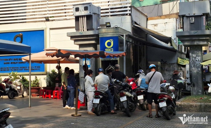 Người dân đứng đăng ký mua vàng miếng trực tuyến trước cửa công ty SJC trưa 23/12. Ảnh: T.C