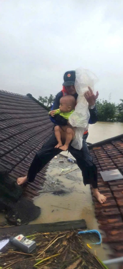 Hình ảnh Thiếu tá Khiên bế em bé đứng trên mái nhà gây xúc động.