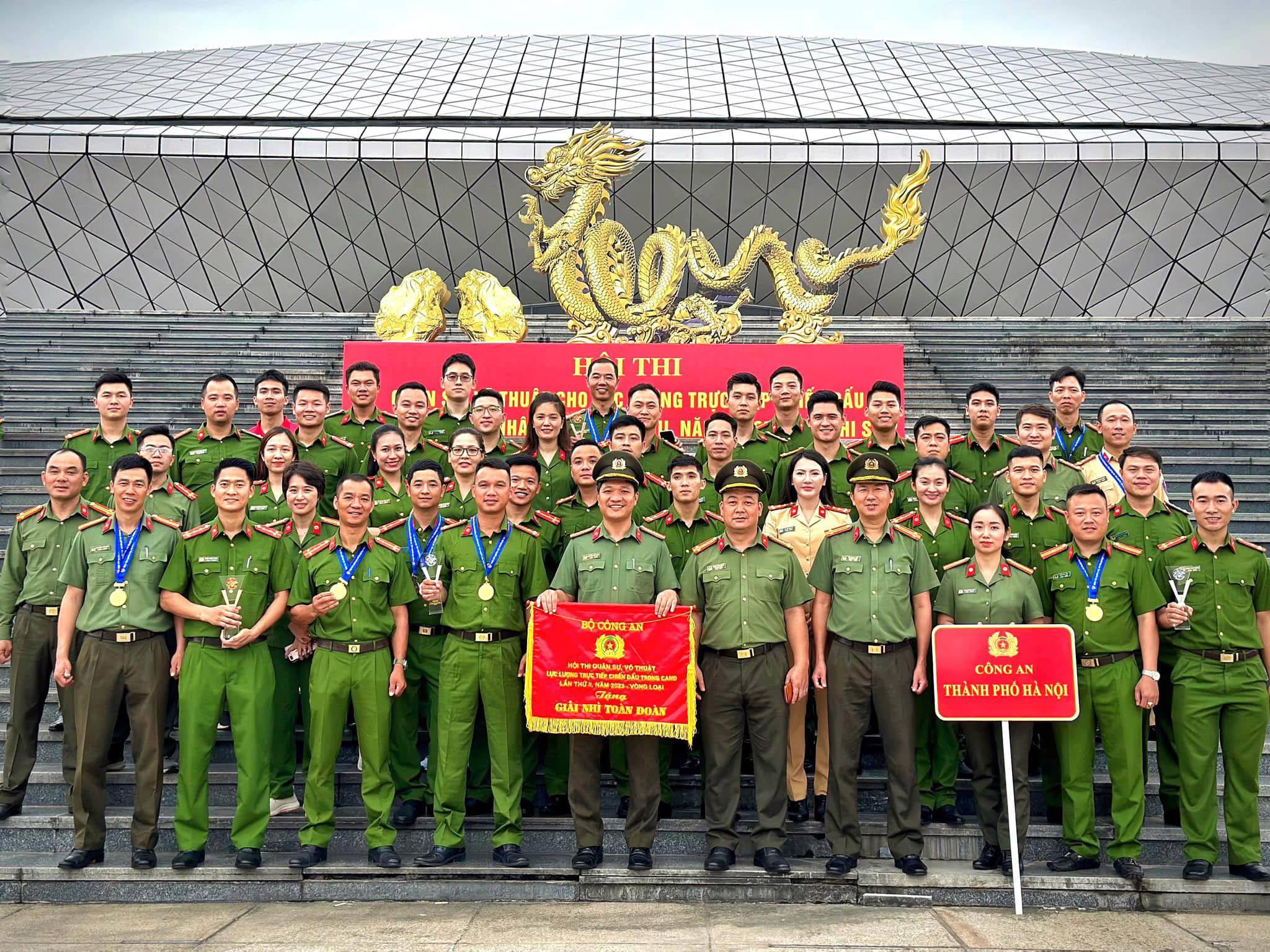 Trung tá Nguyễn Tiến Hưng (cầm cờ ở giữa) và Trung tá Vũ Quang Việt (Phó Đội trưởng Đội điều lệnh, quân sự, võ thuật, CATP Hà Nội)&nbsp;trực tiếp chỉ huy tổ võ thuật CATP Hà Nội.