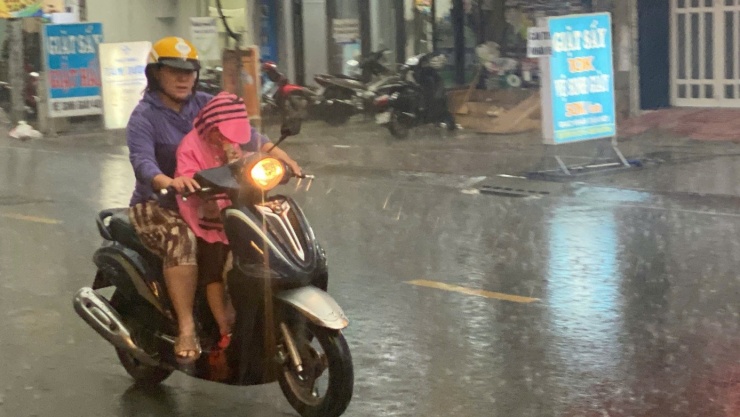 Mưa lớn khiến nhiều người dân phải bật đèn xe để di chuyển trên đường Trần Nhân Tôn.