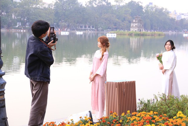 Thợ ảnh tác nghiệp trong một buổi chụp áo dài ngoại cảnh bên Hồ Gươm. (Ảnh: Nhật Anh)