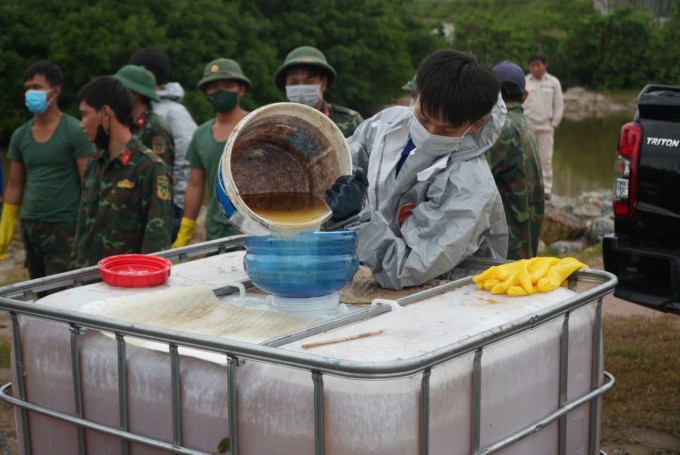 Bộ đội thu gom dầu bỏ vào thùng sáng nay 16/12. Anh: Phạm Linh