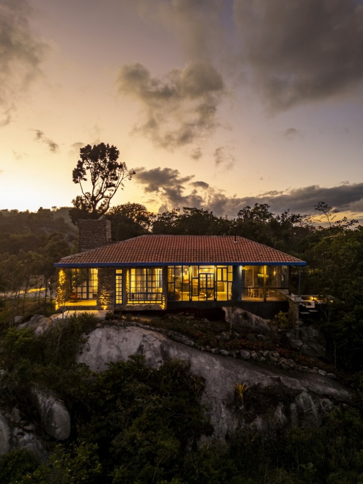 Nhà xanh nổi bật với khung cửa kính và ánh sáng vàng len lỏi giữa rừng.