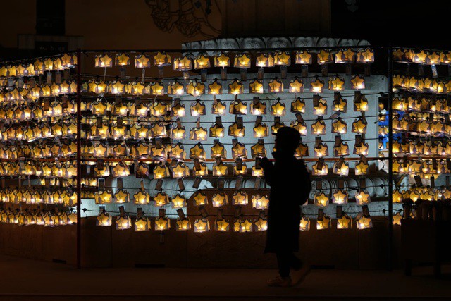 Một Phật tử cầu nguyện trước những chiếc đèn lồng vào đêm giao thừa tại chùa Jogye ở Seoul - Hàn Quốc - Ảnh: AP
