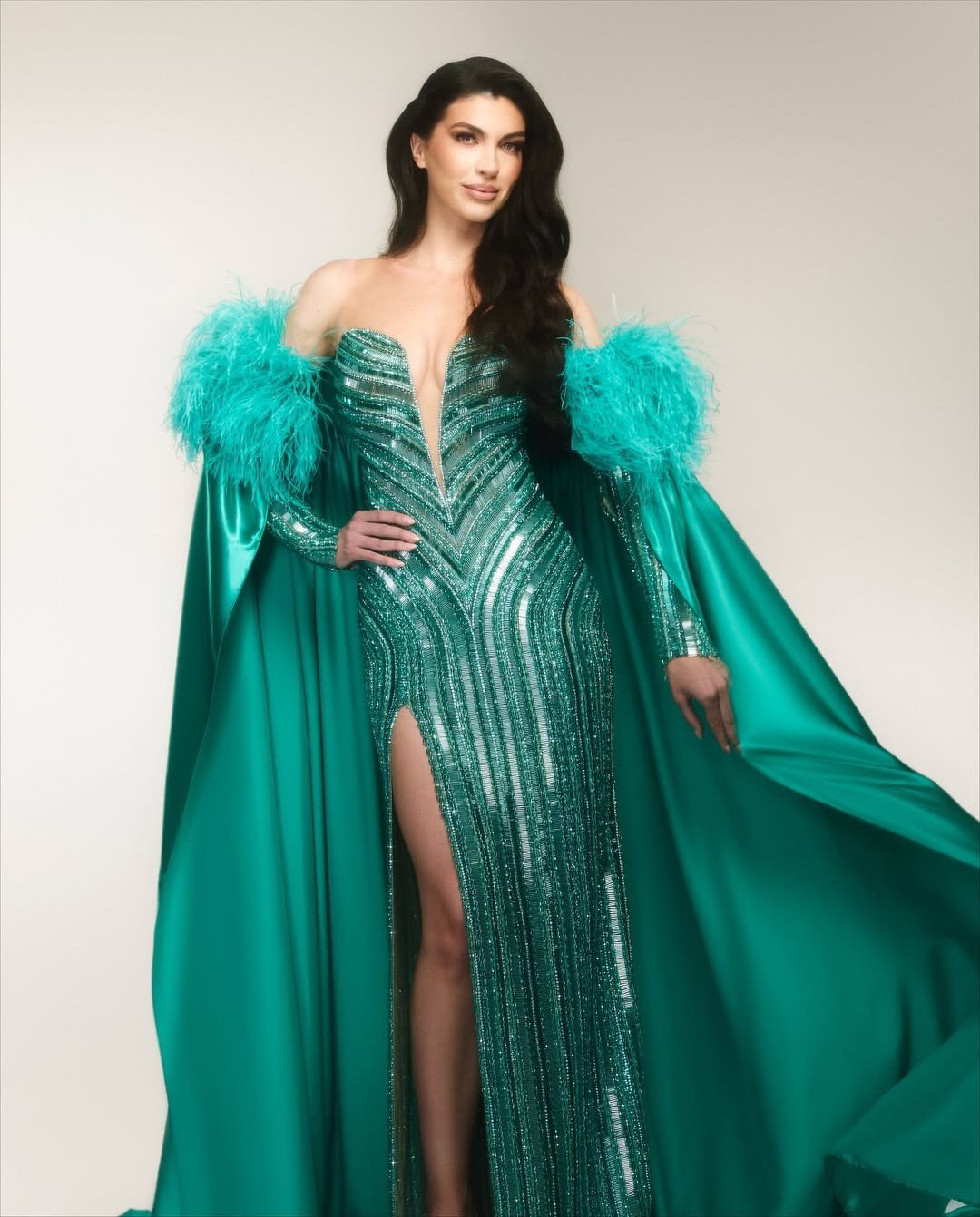 Thiết kế có tông màu xanh, kiểu dáng xẻ ngực, được đính kết đá lấp lánh dọc thân váy. Bộ váy có kết cấu, kiểu dáng khá đơn giản nhưng tôn vóc dáng của người đẹp Brazil. Nhà thiết kế sử dụng thêm áo choàng lông vũ cùng tông màu để bay bổng khi trình diễn.