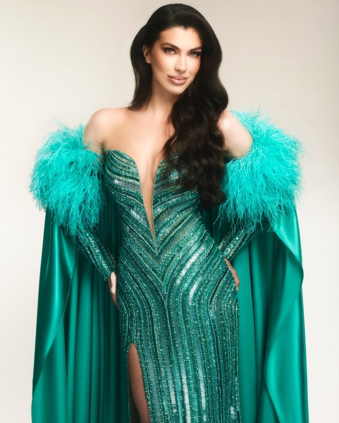 Thiết kế có tông màu xanh, kiểu dáng xẻ ngực, được đính kết đá lấp lánh dọc thân váy. Bộ váy có kết cấu, kiểu dáng khá đơn giản nhưng tôn vóc dáng của người đẹp Brazil. Nhà thiết kế sử dụng thêm áo choàng lông vũ cùng tông màu để bay bổng khi trình diễn.