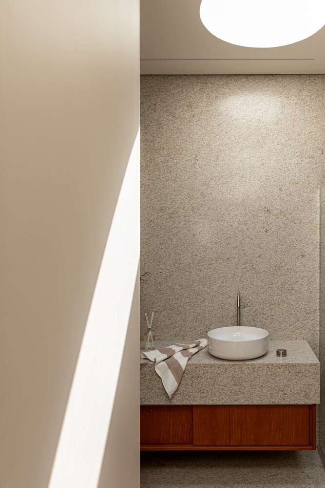 Hai phòng tắm sử dụng đá ở khu vực lavabo, kết hợp tủ gỗ bên dưới.