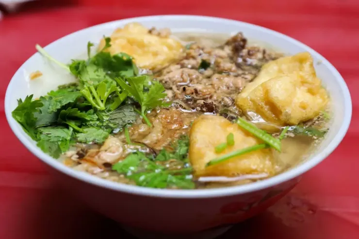 Bánh đúc nóng Bánh đúc nóng có thành phần chính là bột gạo, nấu cho đến khi đặc lại, sền sệt, phần nhân làm từ thịt và mộc nhĩ băm nhuyễn. Khi khách ăn, người bán múc bánh, thêm nhân, chan nước dùng xương nóng và rắc hành khô, hành lá. Mỗi suất thường có giá từ 25.000 đồng. Ảnh: Xuân Phương
