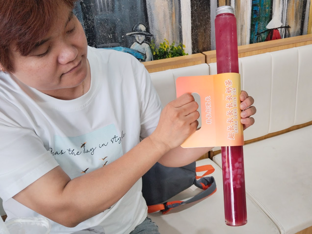 Khách hàng cầm trên tay cốc trà lựu siêu dài.