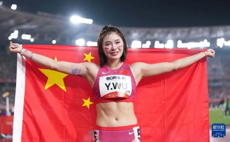 Wu Yanni bật khóc khi khoác quốc kỳ Trung Quốc sau khi giành HC đồng 100 m rào nữ với thành tích 13,12 giây tại sân Mizuho, Nagoya, Nhật Bản tối 27/9/2026. Ảnh: Xinhua