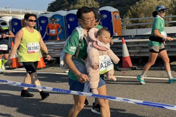 Người đàn ông vừa chạy vừa địu trẻ sơ sinh tại Hong Kong Marathon ngày 18/1/2026. Ảnh: Threads/tam2gogo